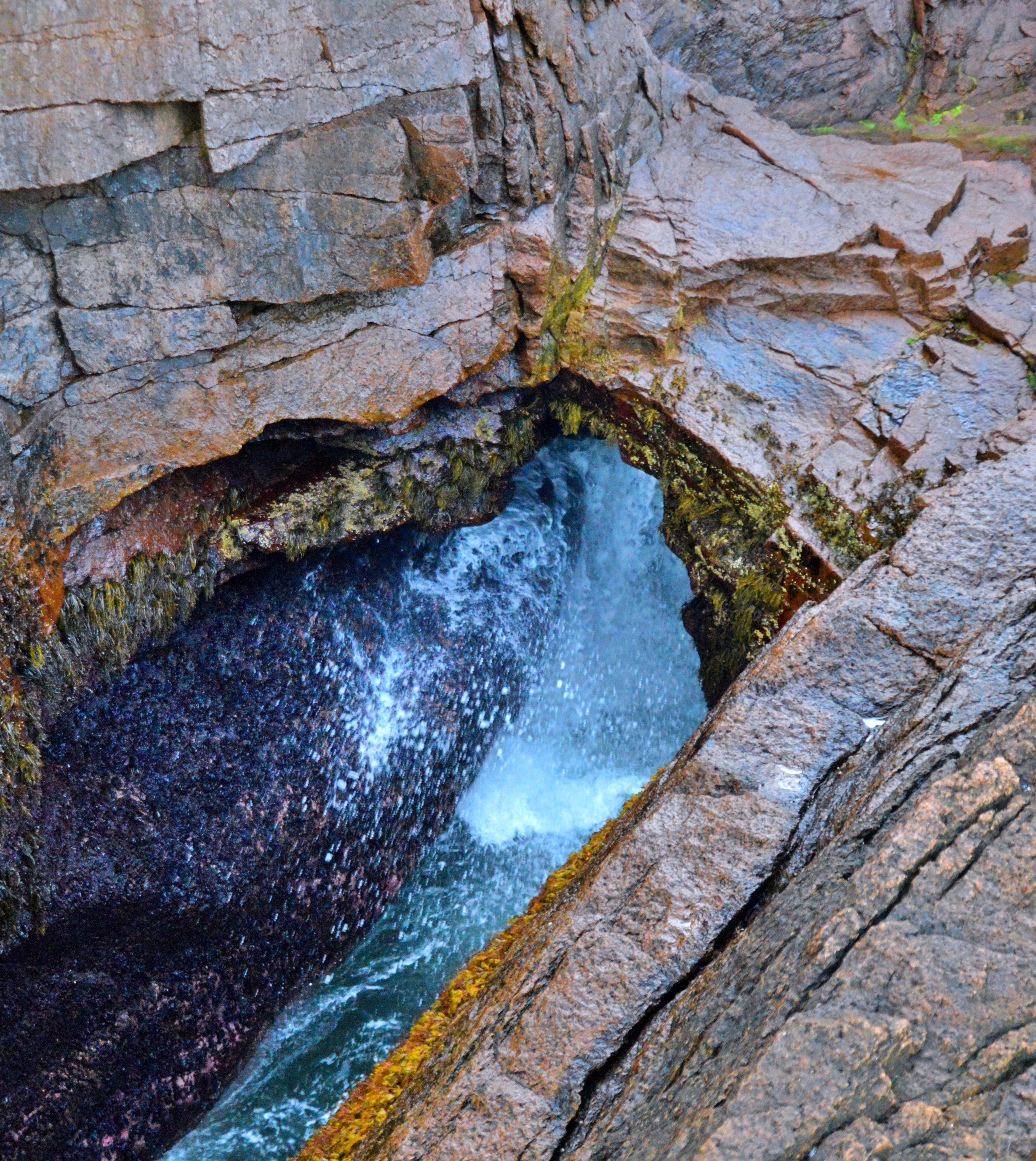 Ocean water surging into Thunder Hole between steep granite cliffs in Acadia National Park