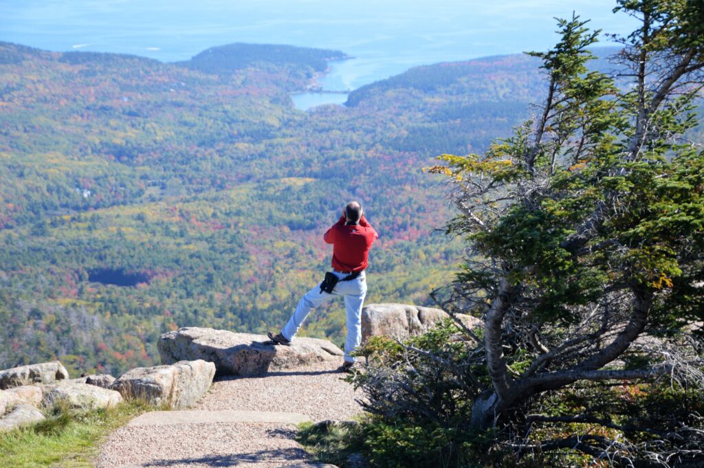 Hike overlooking autumn foliage and rolling hills from the summit of Cadillac Mountain in Acadia National Park