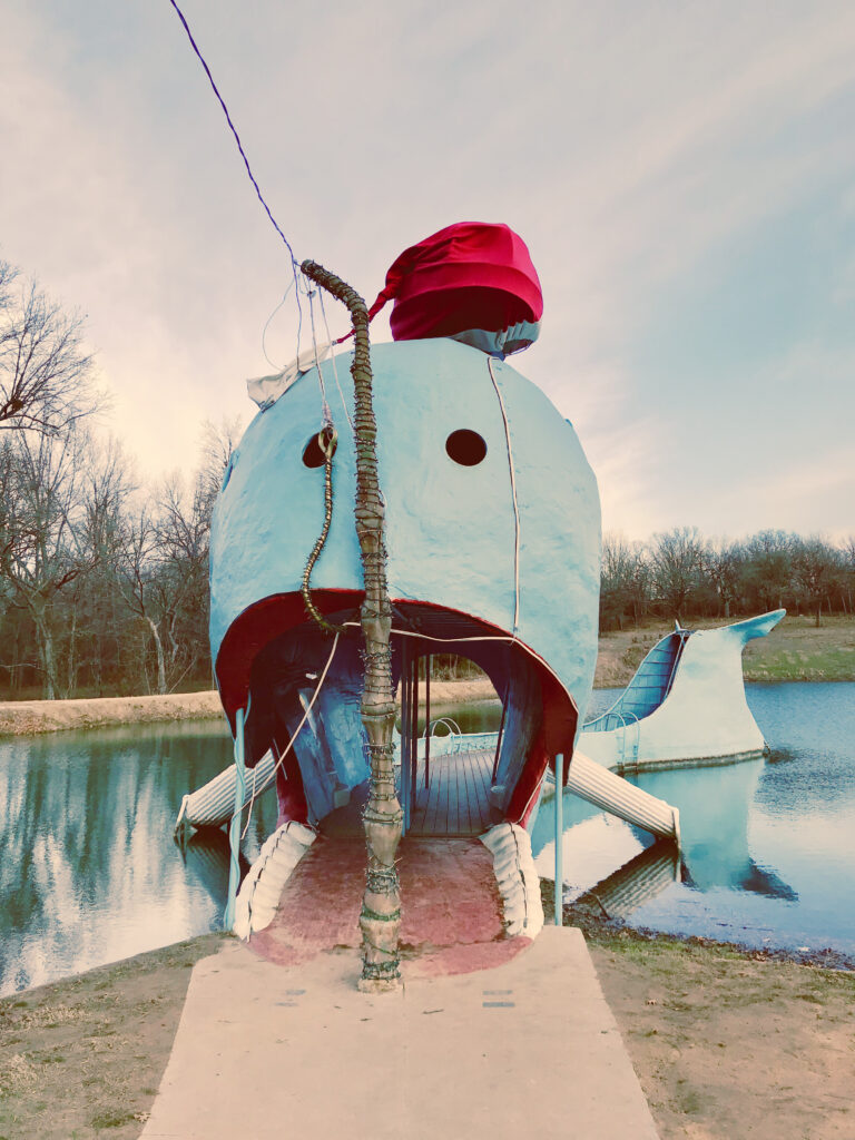 Front view of the Blue Whale of Catoosa showing walkway into the open mouth of the whale, decorated with a Santa hat in winter.