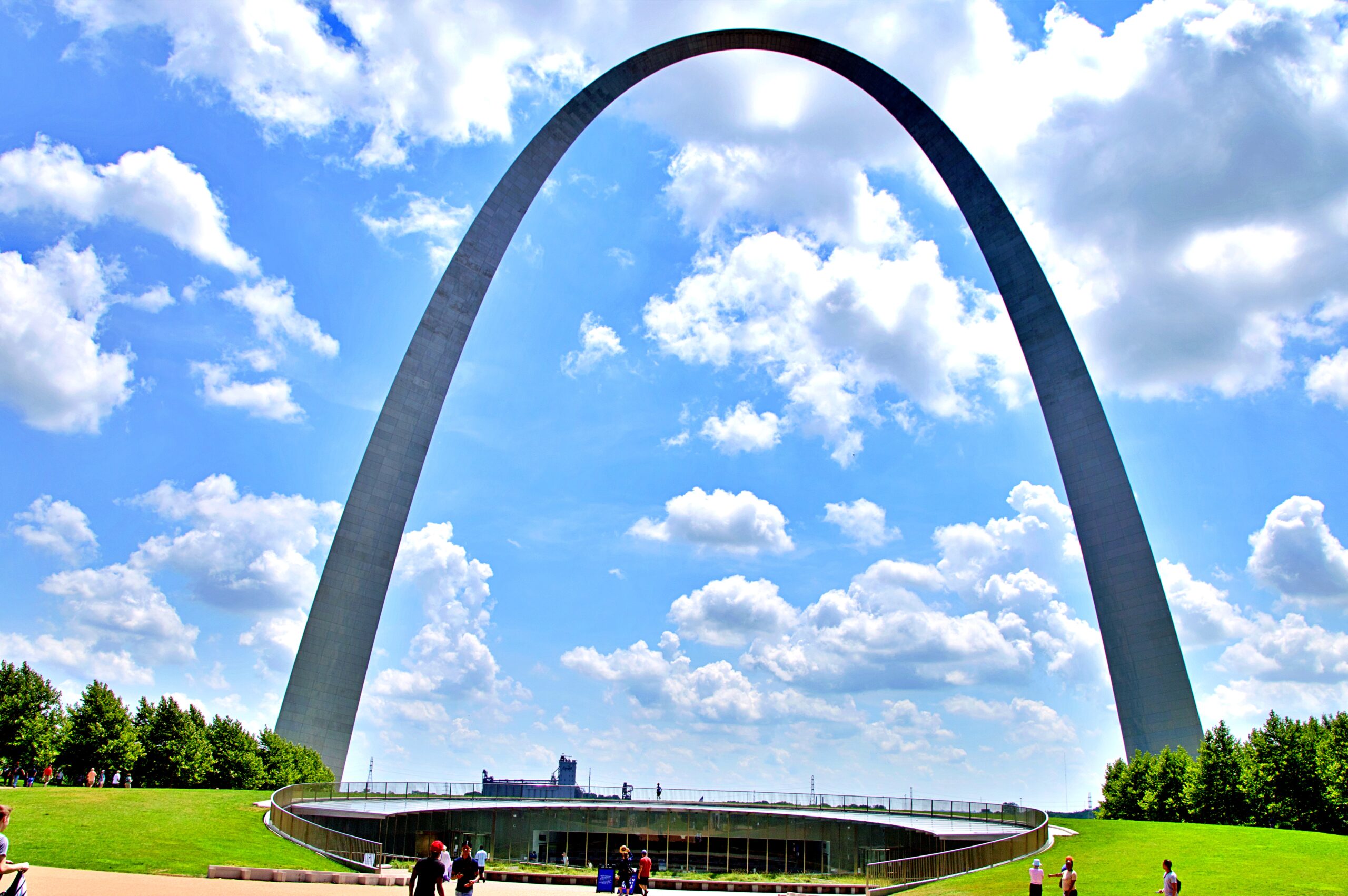 Gateway Arch in St. Louis, Missouri, rising above a green park under a blue sky with scattered clouds
