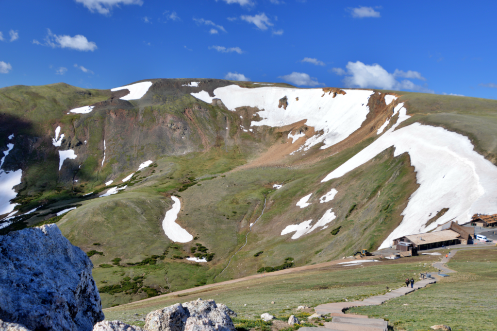 Boardwalk trail through alpine tundra near the Alpine Visitor Center in Rocky Mountain National Park, with a snow-streaked mountain ridge in the background