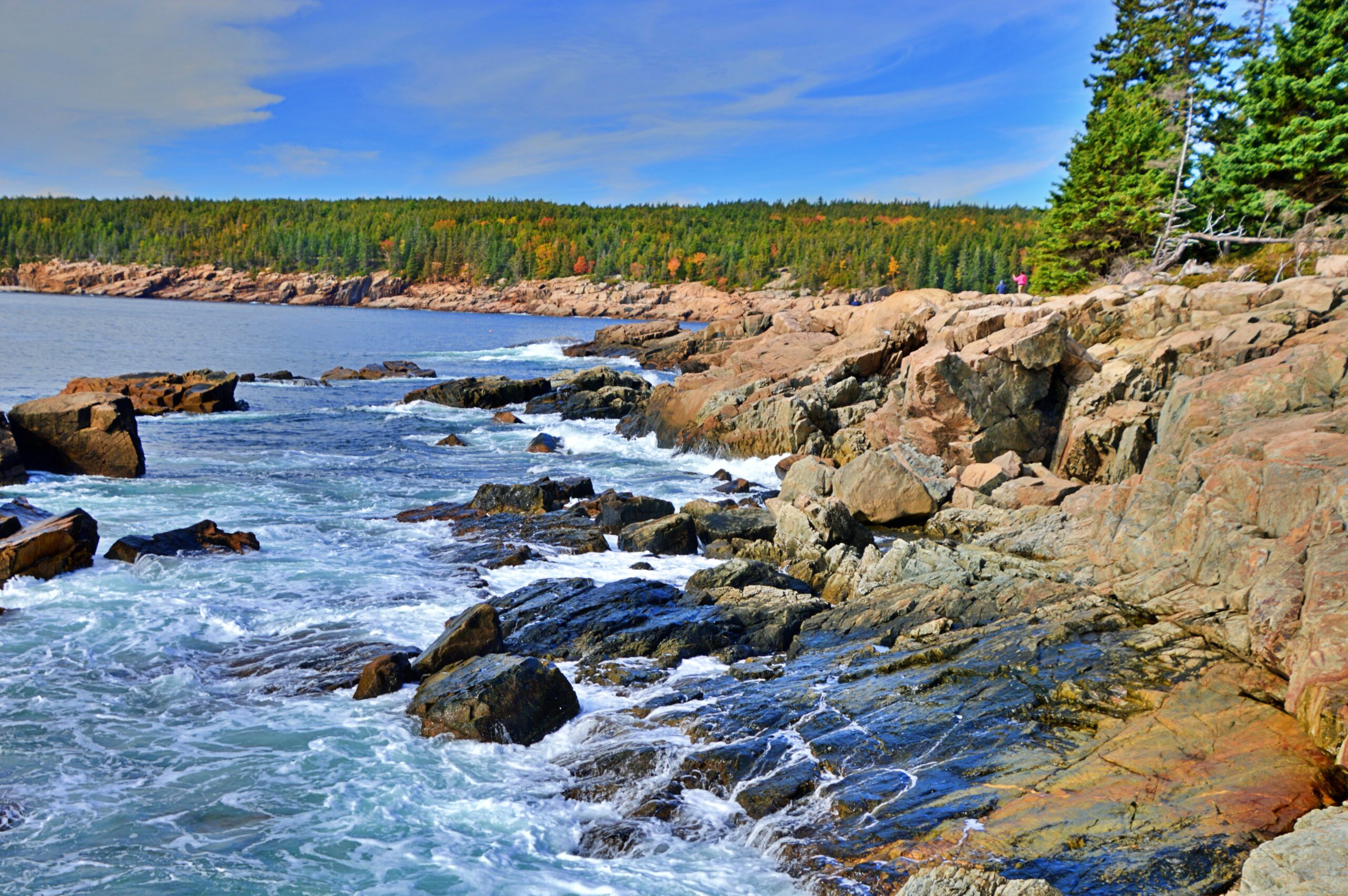 Waves crashing against pink and gray granite rock formations along the Ocean Path near Otter Cliffs in Acadia National Park