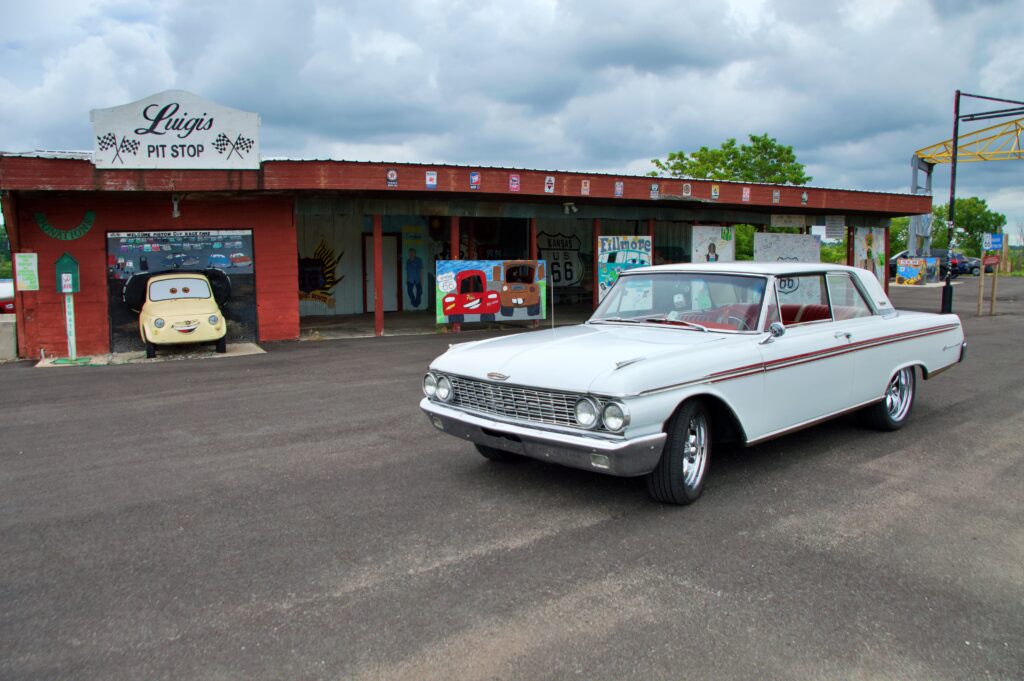 Luigi's Pit Stop in Galena, Kansas, with a vintage white Ford parked out front and Cars-themed murals painted on the building