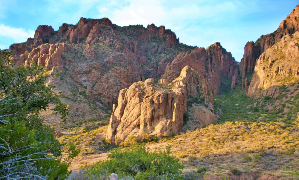 Sunlight illuminates rugged rock spires and canyon walls in the Chisos Basin at Big Bend National Park