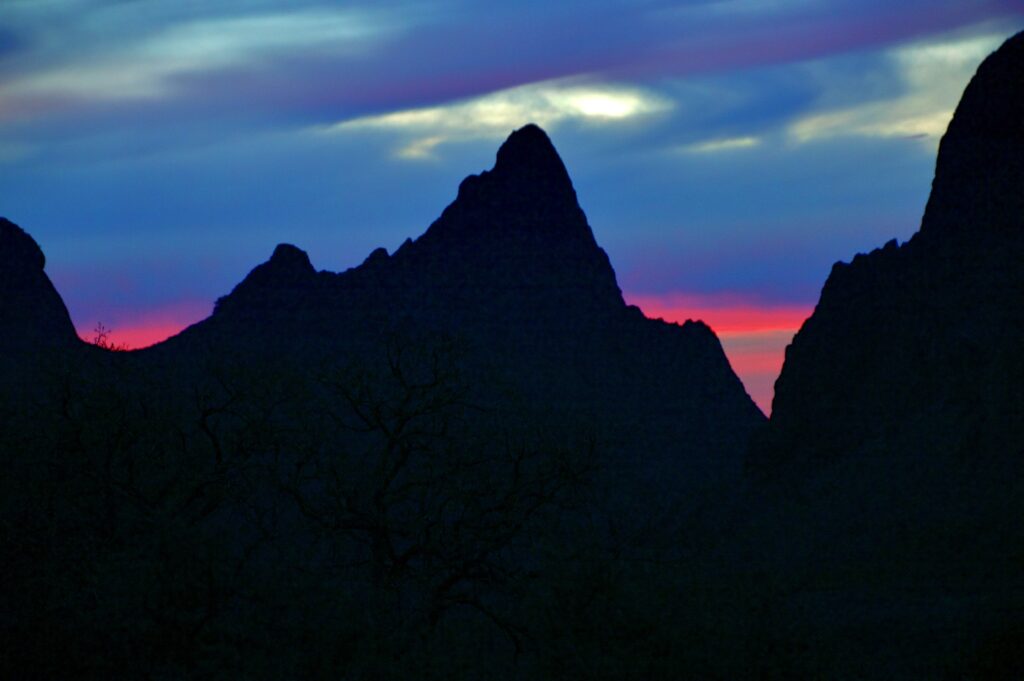 Dusk light fades in shades of blue and pink behind The Window, a notch in the peaks of the Chisos Basin at Big Bend National Park