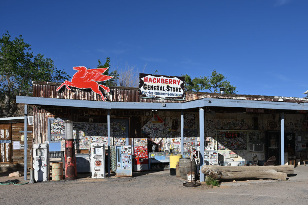 Hackberry General Store on Route 66, a rustic tin-sided building covered in stickers and vintage signage, with old gas pumps and a red flying horse sign out front