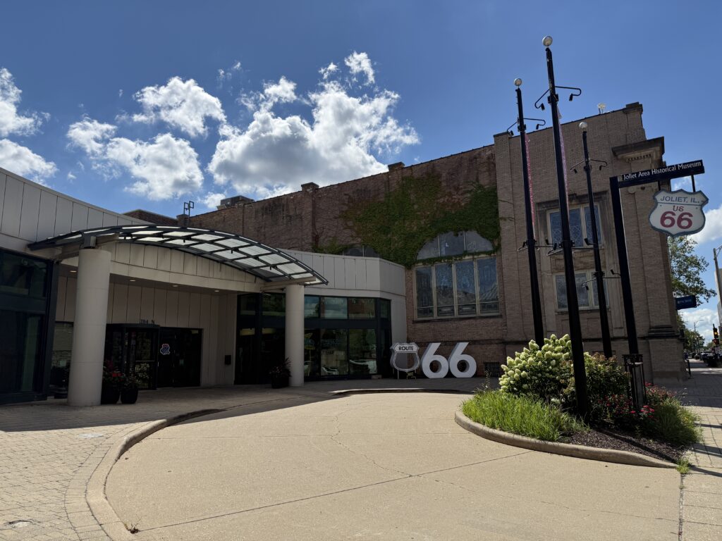 The entrance to the Joliet Area Historical Museum with a large Route 66 shield sign and "66" numerals displayed outside
