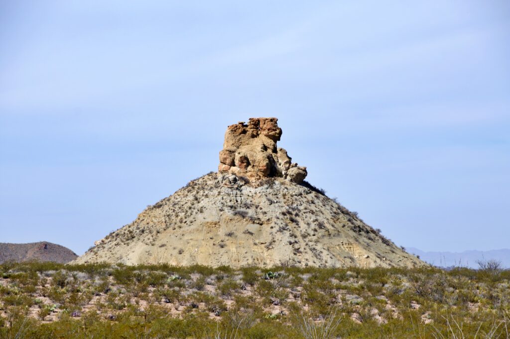 Sphinx Rock, a distinctive eroded rock formation atop a cone-shaped hill, rises above the desert along Ross Maxwell Scenic Drive in Big Bend National Park