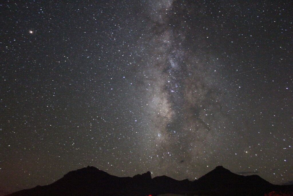 The Milky Way stretches across a star-filled sky above dark mountain silhouettes near Panther Junction in Big Bend National Park. (NPS Photo/T. Jurado)