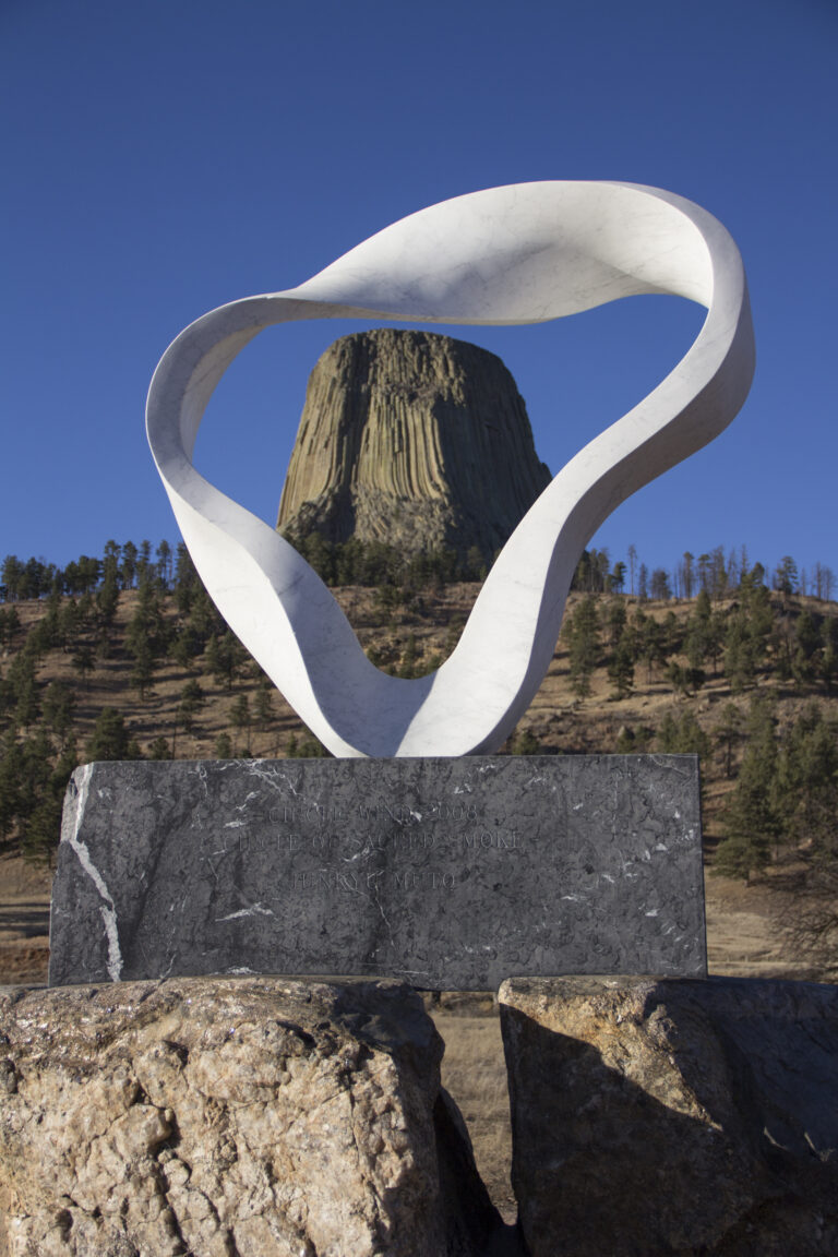 Circle of Sacred Smoke, a white marble sculpture by Junkyu Muto framing Devils Tower against a blue sky