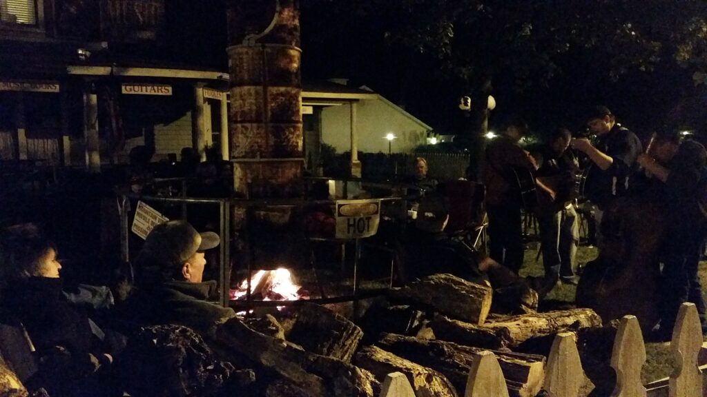 Musicians and listeners gathered around a fire outside a music shop in downtown Mountain View, Arkansas, at night