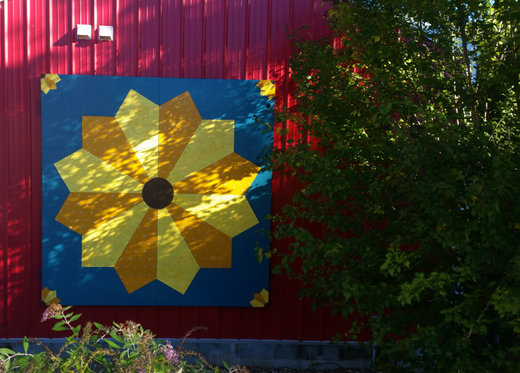 Sunflower-pattern painted quilt square mounted on a red barn wall in Stone County, Arkansas