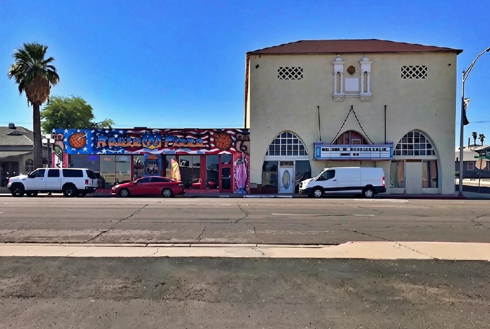 The historic Needles Theatre building at F Street and Broadway in Needles, California, with a 'Welcome to Needles Calif' marquee and Route 66 Pizza storefront beside it