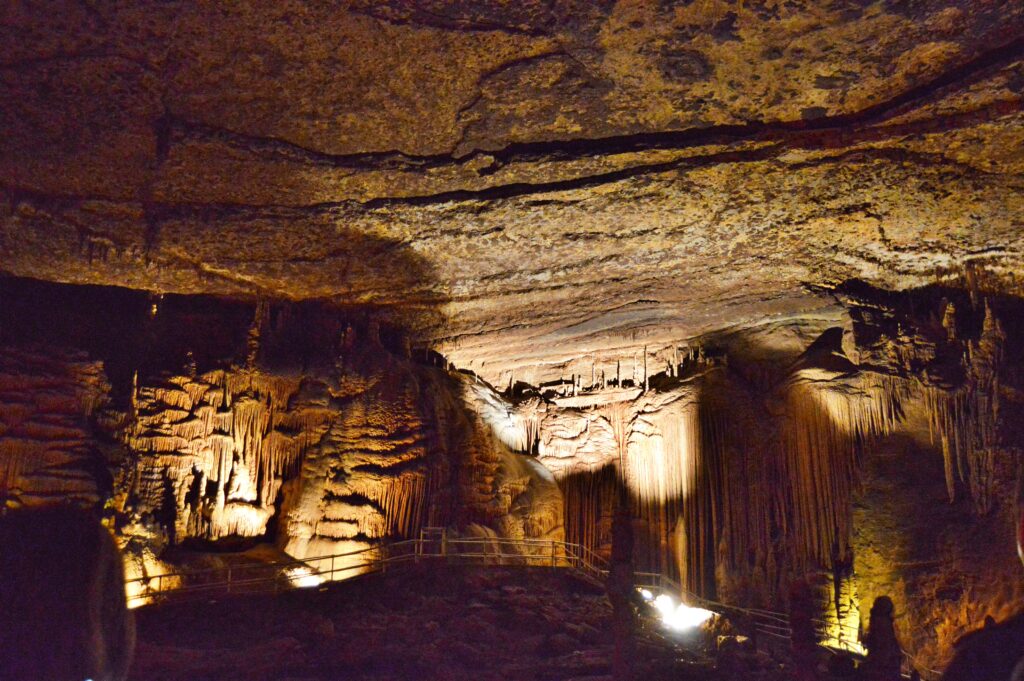 Wide view of a cavern chamber at Blanchard Springs Caverns with formations lining the walls and a visitor silhouette for scale
