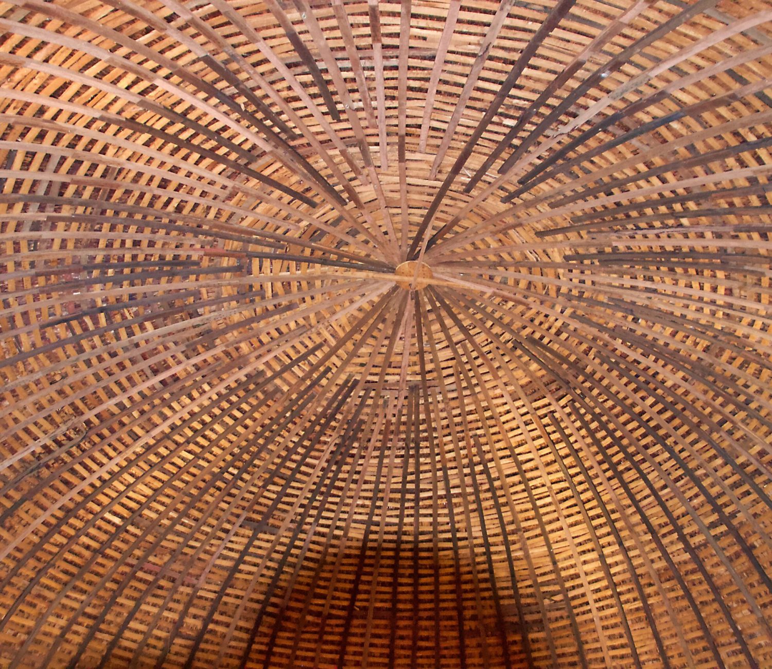 Interior view of the Arcadia Round Barn showing a symmetrical network of curved wooden rafters forming a circular pattern overhead.